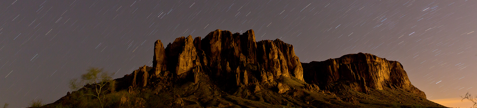 Long exposure night image of the Superstition Mountains with stars streaking above the mountains