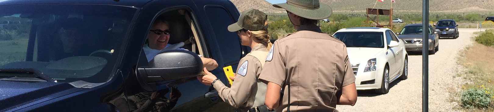 Two rangers talk to a visitor in a truck at one of the amazing state parks