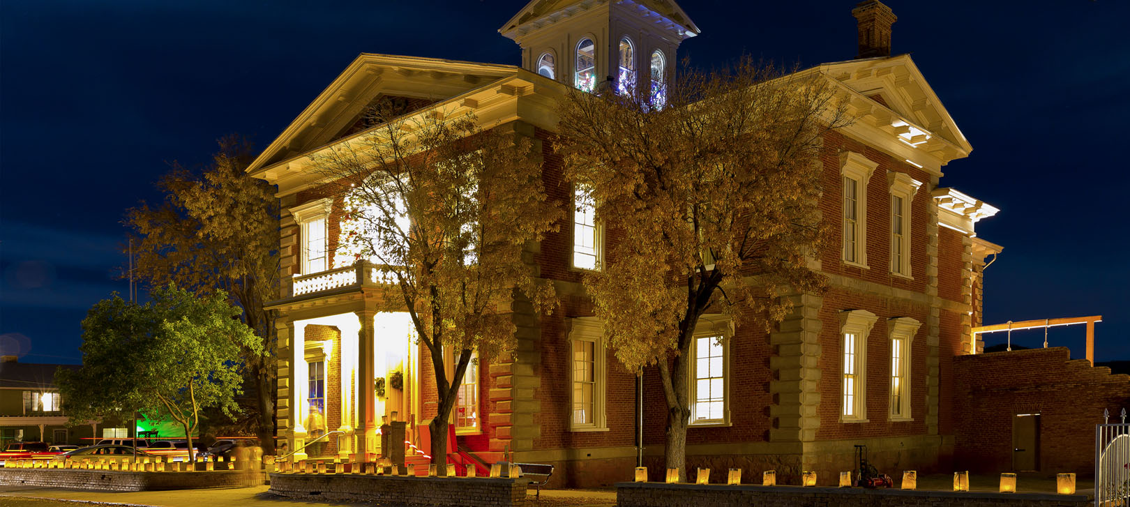 A nighttime view of the Tombstone Courthouse, with lights shining through windows