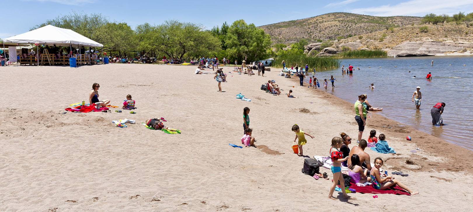 People relax on the beach and in the water at Patagonia Lake State Park