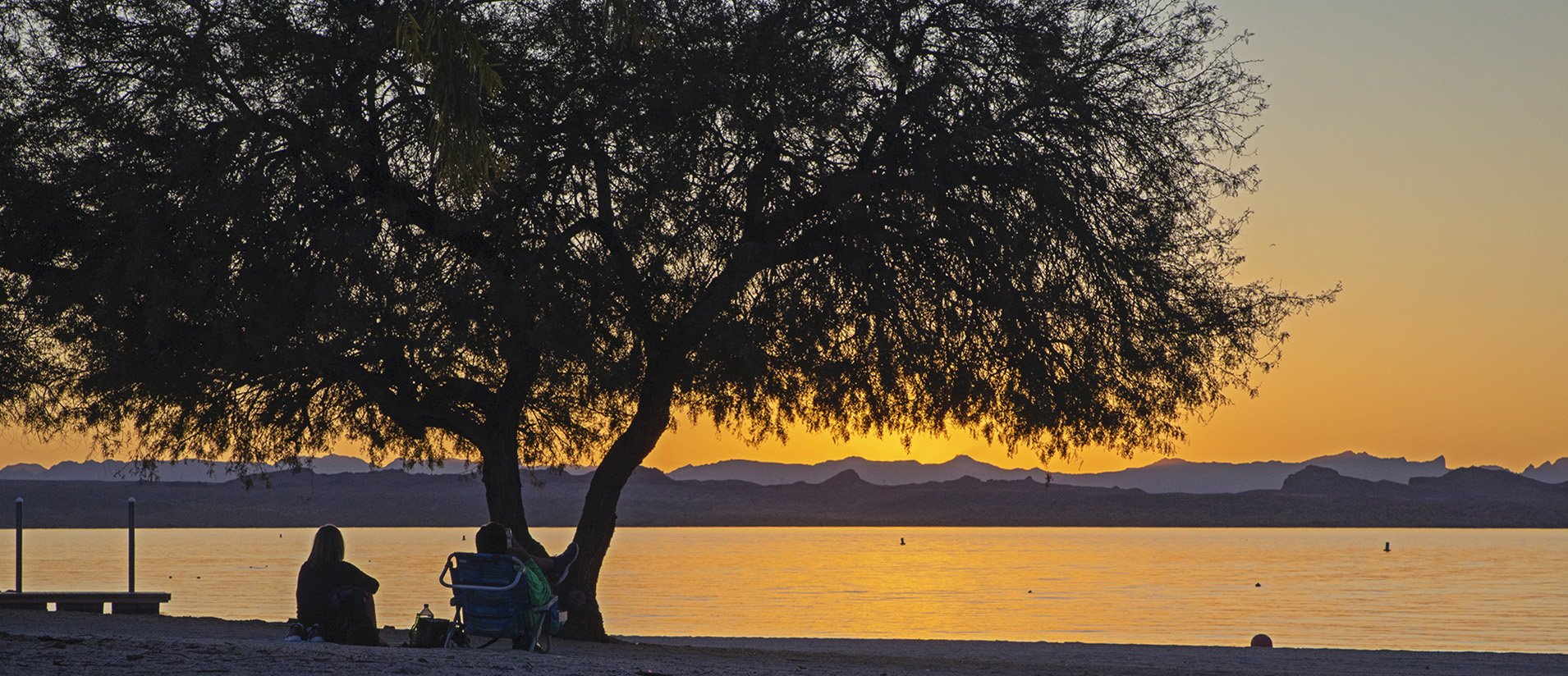 Two campers enjoy sunset over the water at Lake Havasu State Park