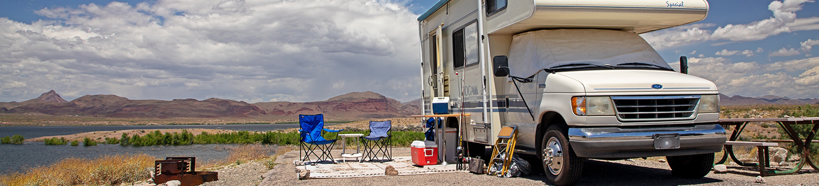 An RV campsite on a partly cloudy day overlooking Alamo Lake in the background.