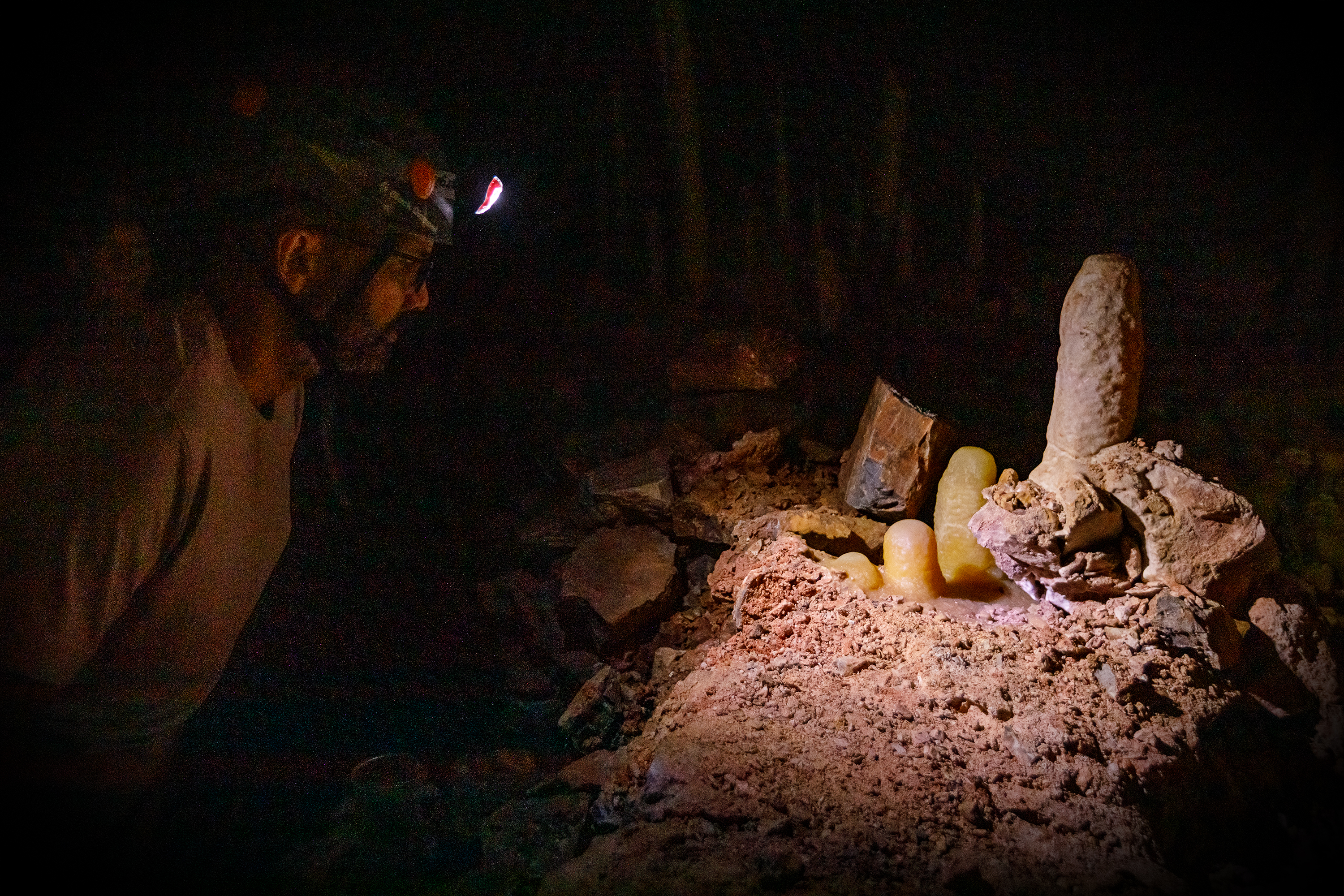 A visitor wearing a headlamp shines the light on a cave formation during the Helmet & Headlamp tour