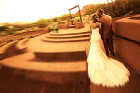 A bride and groom stand in the amphitheater looking toward the stage and scenery beyond.