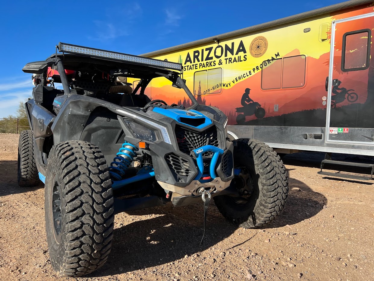 An off-highway vehicle sits next to the  Arizona State Parks and Trails trailer