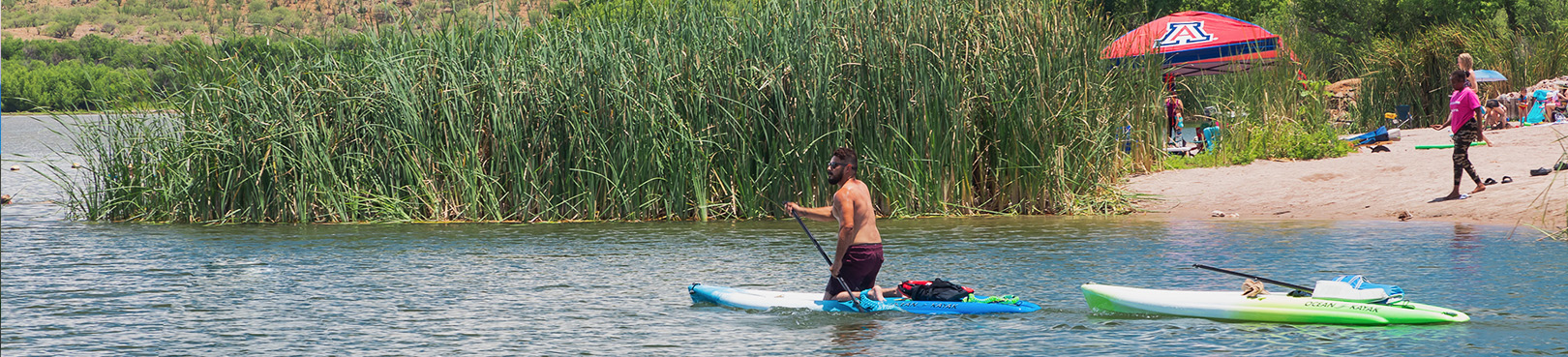 A lone paddleboarder is seen leaving the beach area paddling toward the open water and untold adventures of Patagonia Lake.