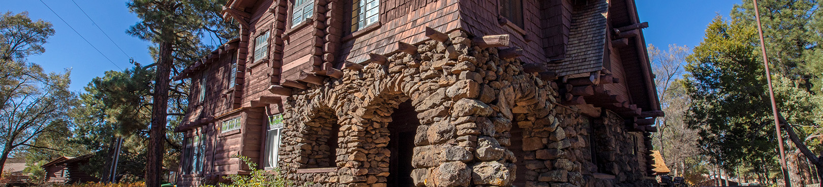 Flagstaff's most visited log cabin, the Riordan Mansion, stands tall amid the ponderosa pine trees under a bluebird sky.