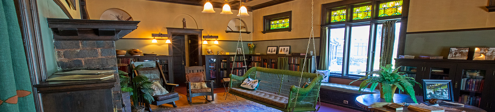 A curated room inside the Riordan Mansion museum displays period furniture and decor including a bench swing in the middle of the room.