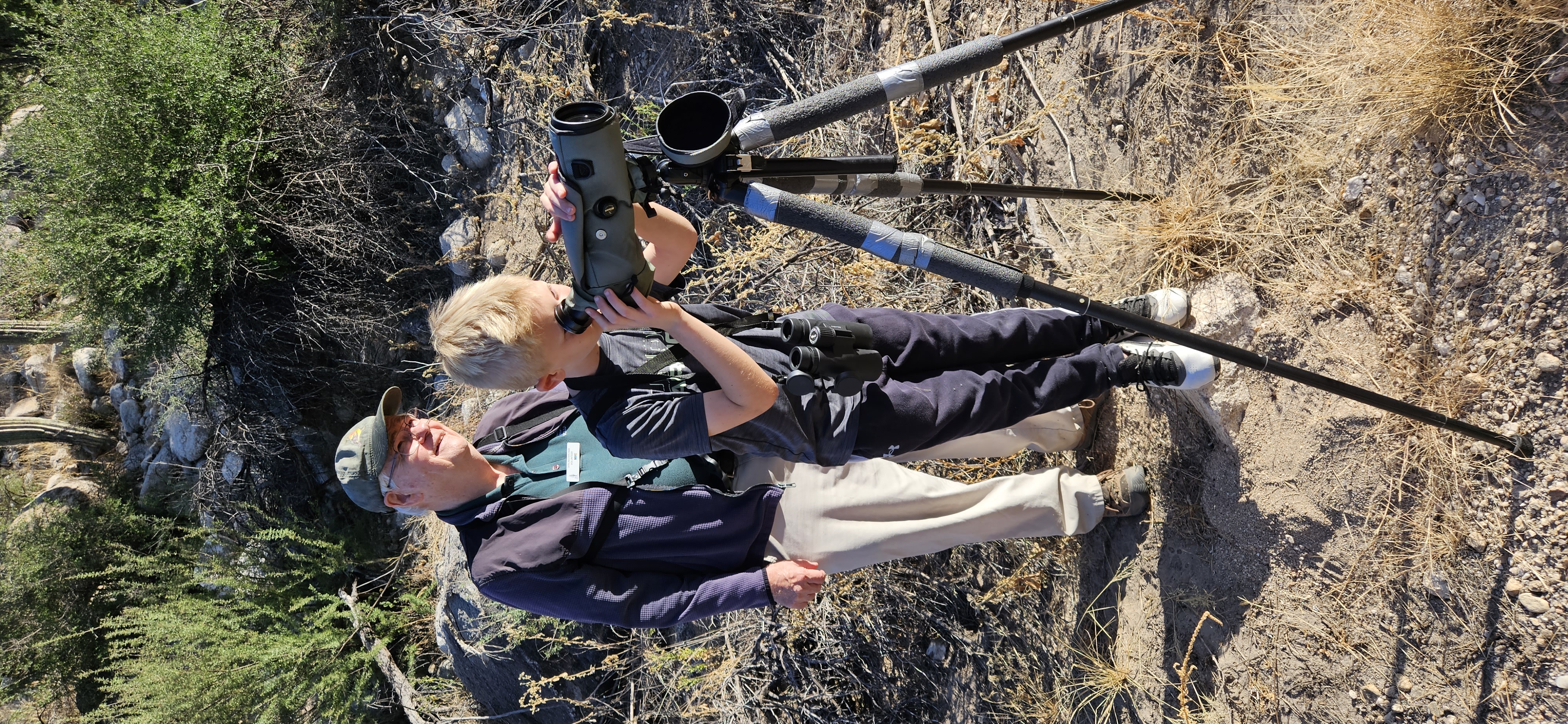 A volunteer and young person use mounted binoculars to find birds at Catalina State Park