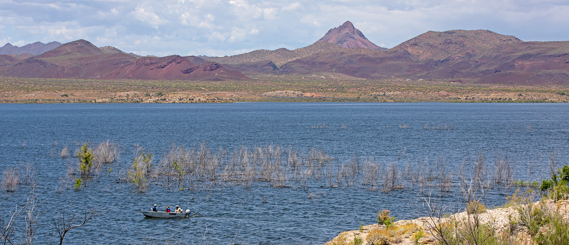 A small boat in the water with purple mountains in the background