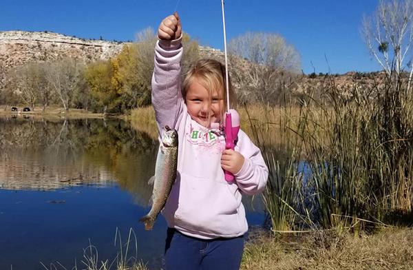 A happy angler and her prize. CHild in pink sweatshirt and fishing pole with a trout caught at Dead Horse Ranch State Park.