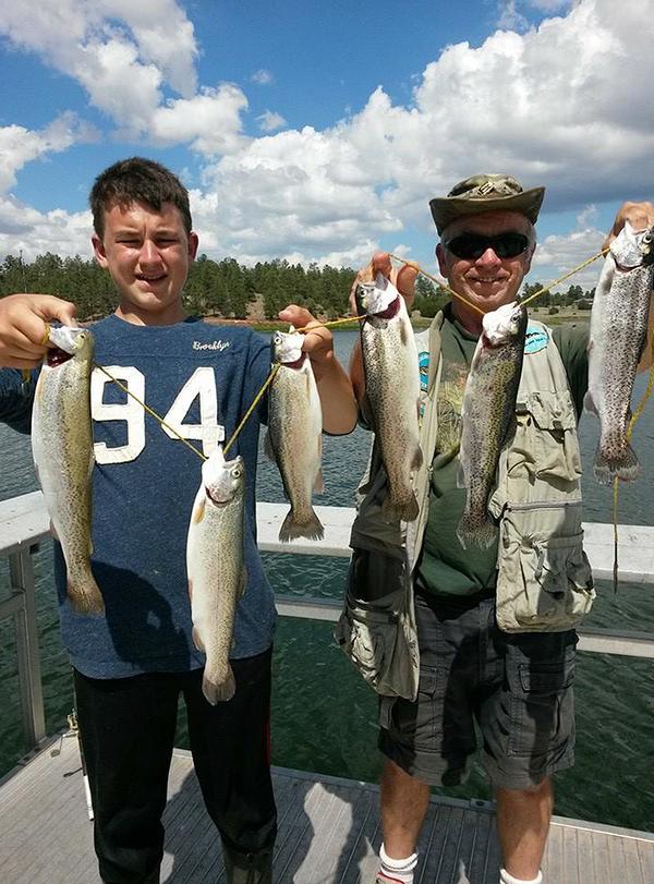 A photo of two people holding up two caught fish each. 