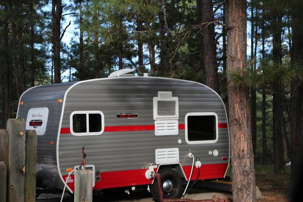 Travel trailer in a campsite at Fool Hollow Lake surrounded by pine trees