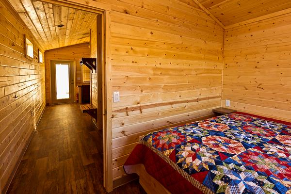 A view inside the cabin at Lake Havasu, with the natural wood walls and floors and a queen-sized bed