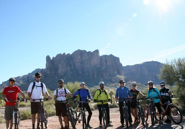 A group of mountain bikers pose in front of the Superstition Mountains at Lost Dutchman State Park.