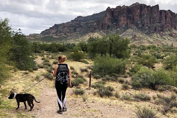 A woman and leashed dog hiking at Lost Dutchman 