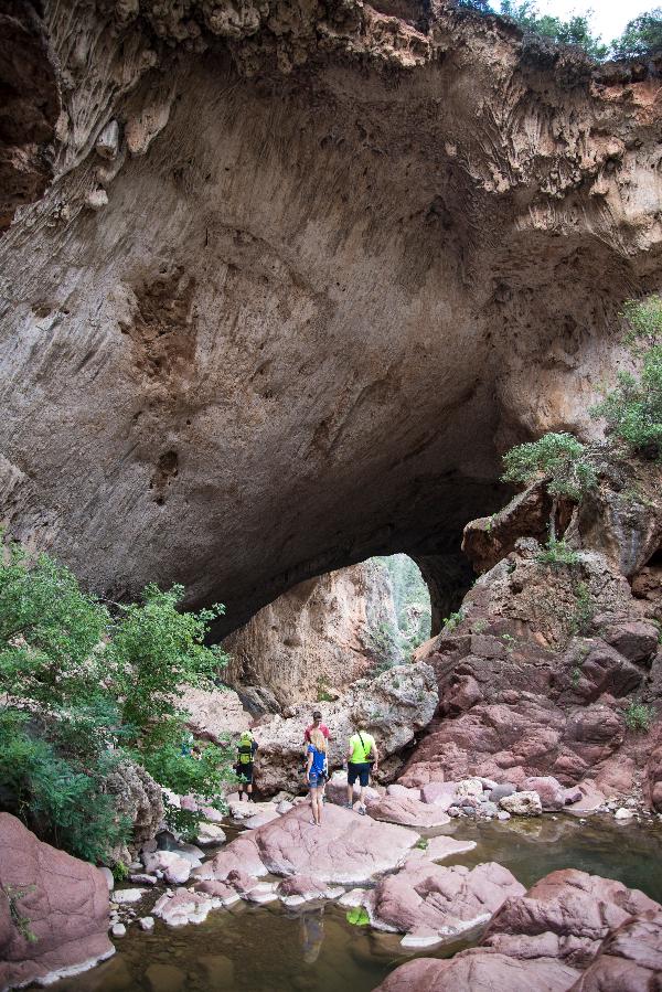 Two hikers stand in the rocks in Pine Creek under Tonto Natural Bridge 