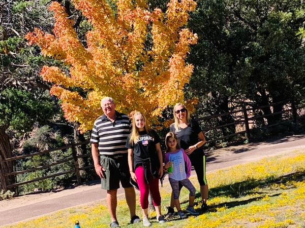 A family visits Tonto Natural Bridge and poses in front of fall colors