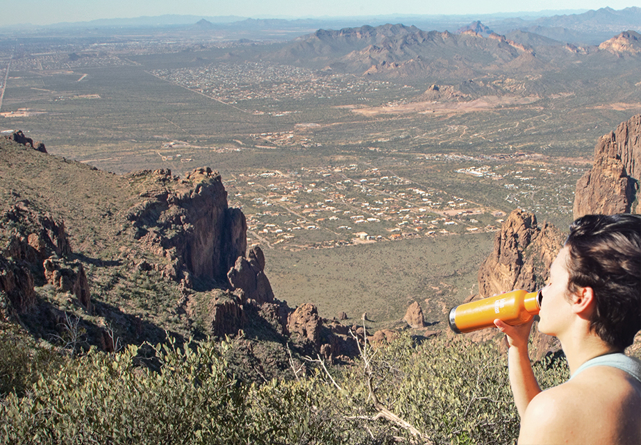 Woman drinking water and taking in the view from the top of Siphon draw in the Superstition Mountains. 