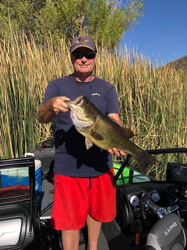 Angler at Patagonia Lake holding a trophy largemouth bass he caught during the summer
