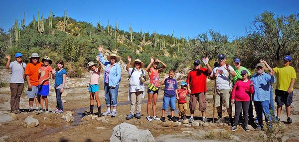 A group of kids and parents wave during a hike at Catalina State Park