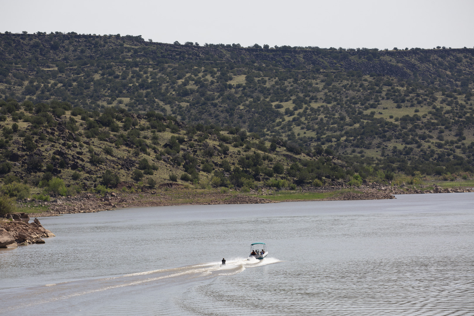 A boat with a water skier flies across the surface of Lyman Lake