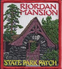 A girl scouts patch for Riordan Mansion State Park with an image of a wooden arched gate and pine trees.