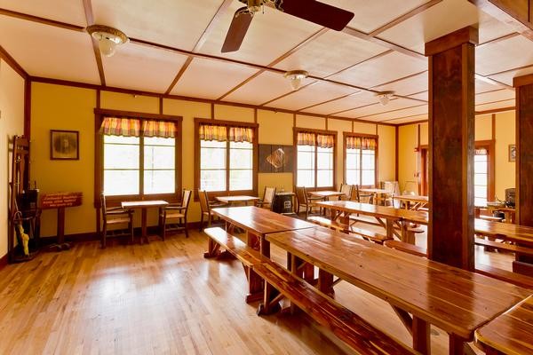 The indoor dining hall in Goodfellow Lodge, with long wood tables and bench seating