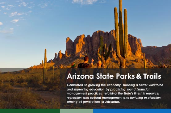 Man and woman at sunset pointing at the Superstition Mountains. Graphic contains an agency commitment about protecting and managing natural resources..