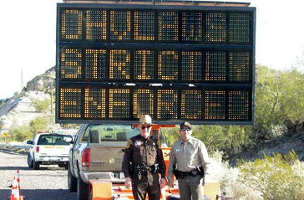 A digital display sign states that OHV laws enforced 